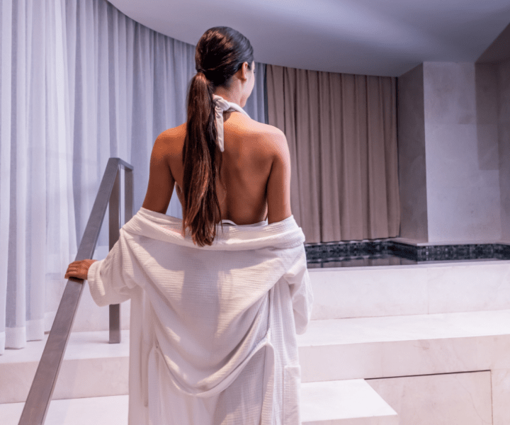 a woman with a white robe ascending a staircase at the spa