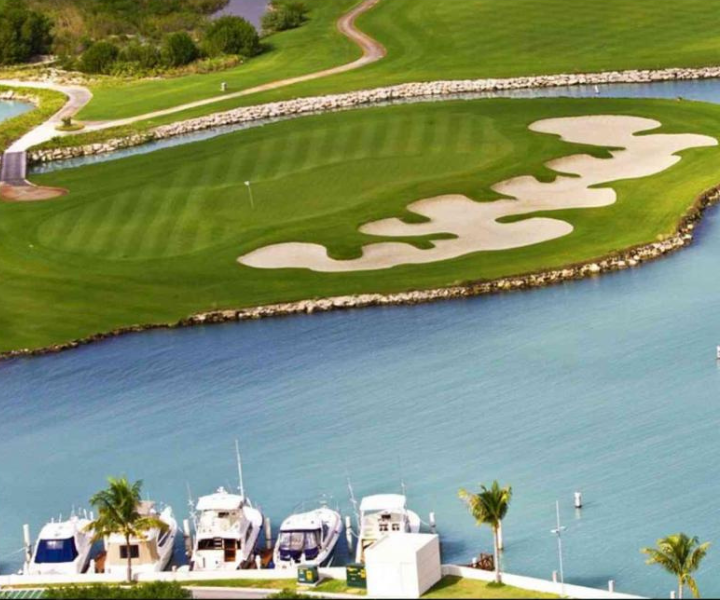 an aerial shot of a green golf course on the water