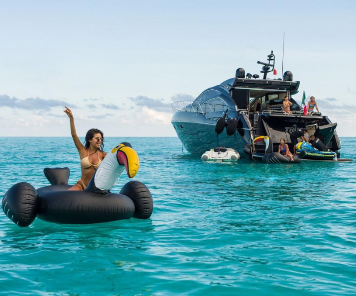 a woman in the ocean with a luxurious yacht in the background
