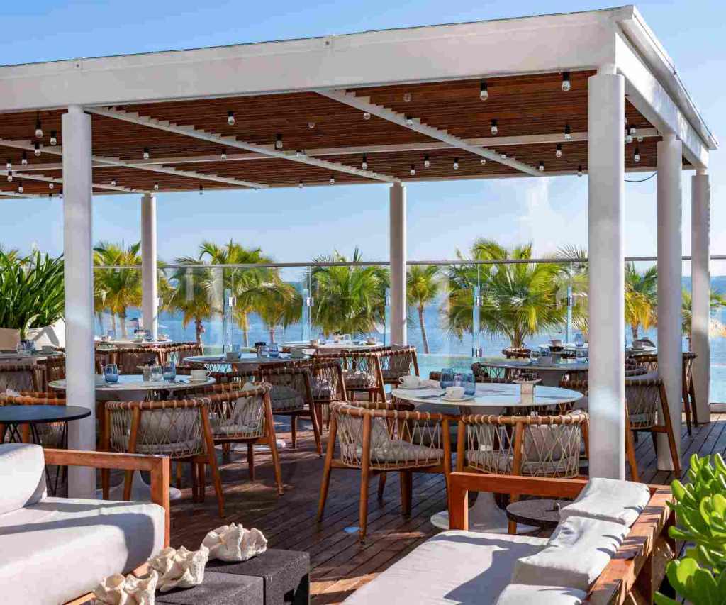 spacious outdoor dining patio with tables and chairs overlooking the ocean