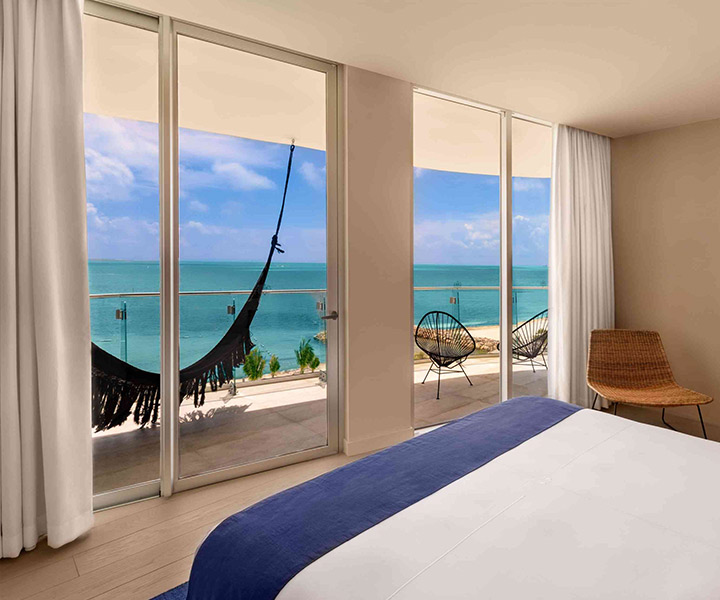 Luxurious bedroom with a balcony with a hammock overlooking the ocean.