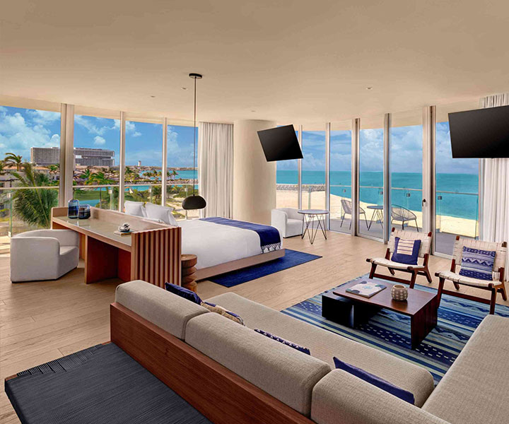 A lavishly adorned bedroom, offering a breathtaking ocean vista and two sleek televisions.