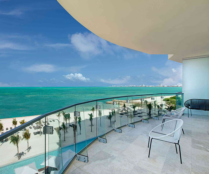 Luxurious balcony with stunning ocean views and sandy beach below.