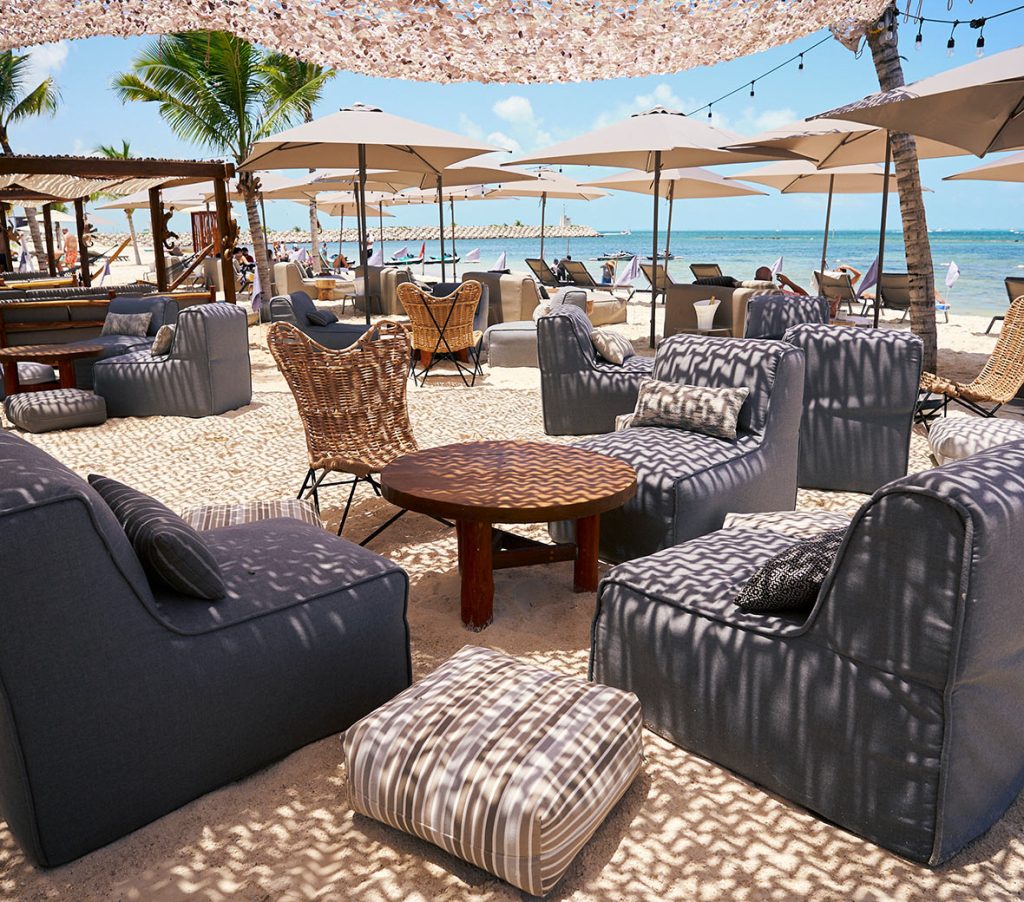 Scène de plage luxueuse avec des chaises élégantes et des parasols élégants sur du sable doré.