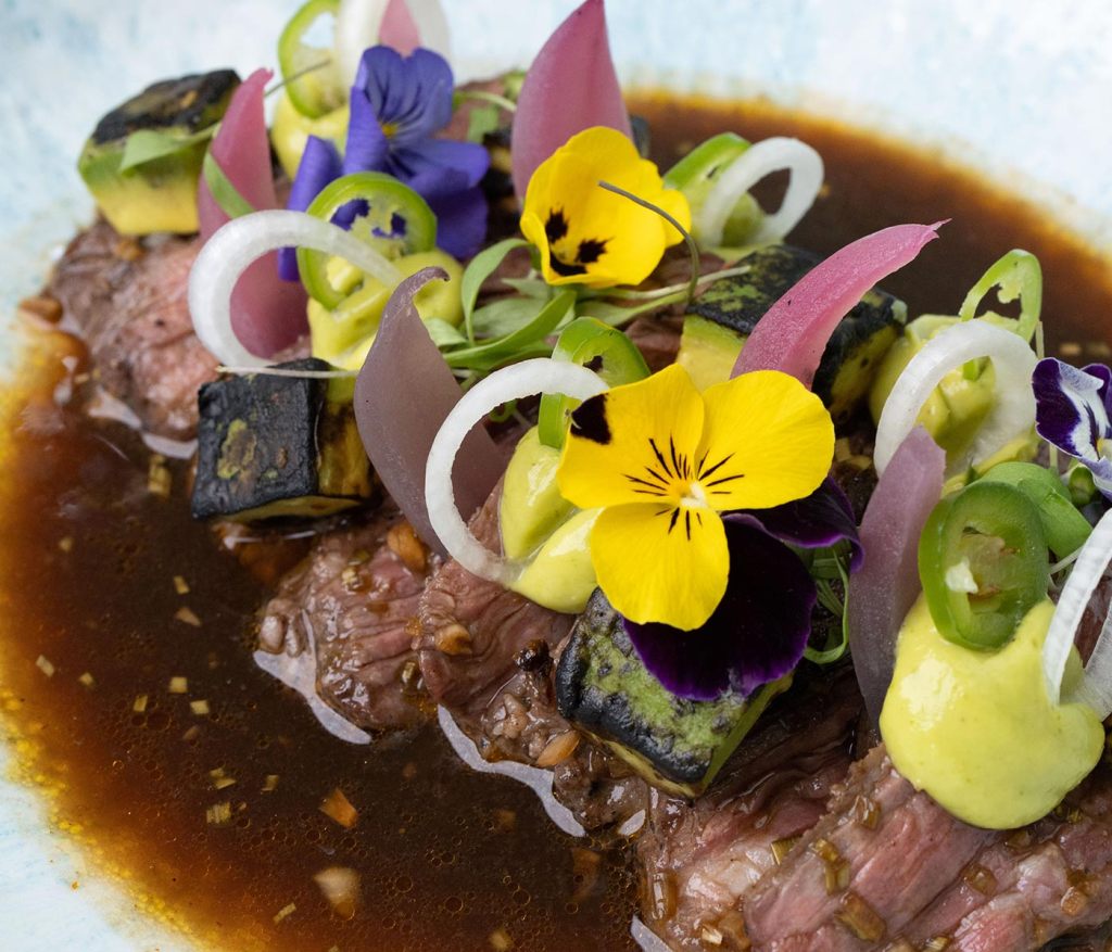 Platillo de carne de res de Lenyia Cancún cubierto con flores