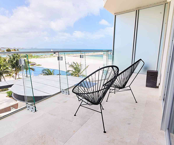 Elegant balcony with two chairs, offering a mesmerizing view of the beach's serene beauty.