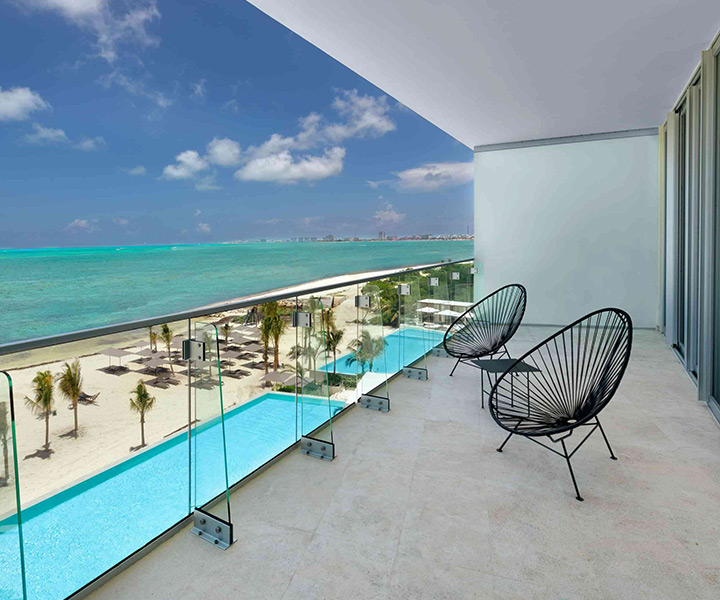serene balcony adorned with elegant chairs, offering a breathtaking vista of the endless ocean and pristine beach.