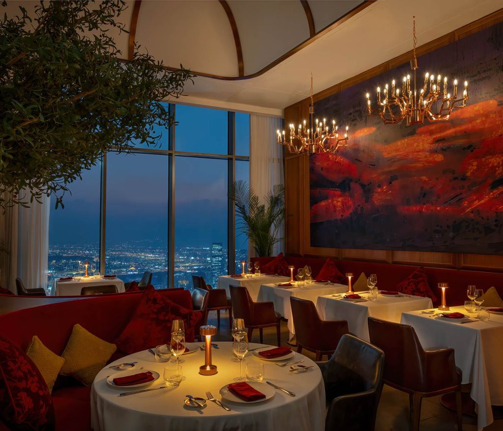 The dining room of Carna Dubai with curved red banquet seating