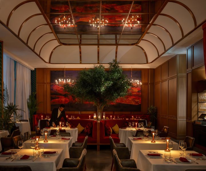 Interior de um restaurante formal com mesas com toalhas de mesa brancas, iluminadas à luz de velas.