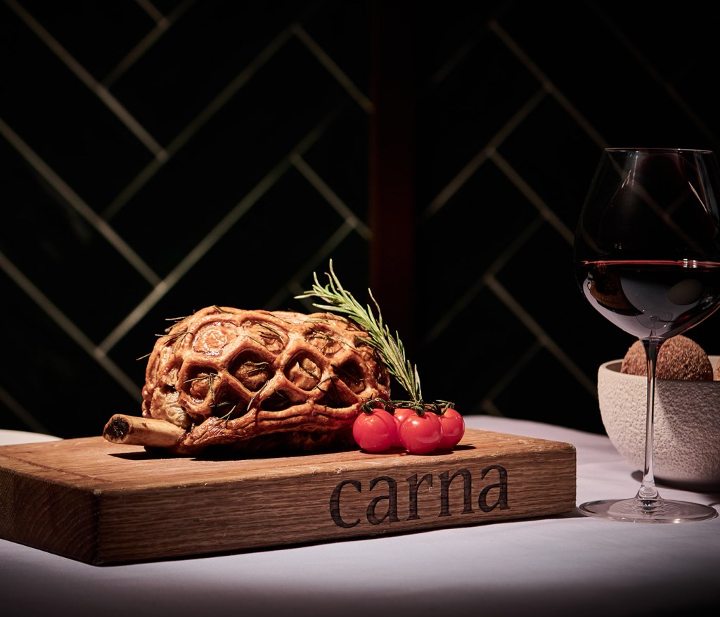 Short rib wellington dish on a cutting board with a glass of red wine