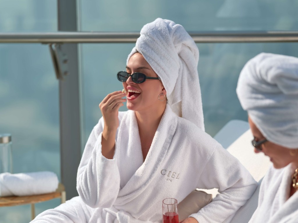 Two women in Ciel Spa robes sitting on the rooftop eating