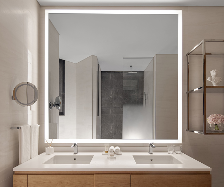 Brighlty lit bathroom with large mirror and two sinks.
