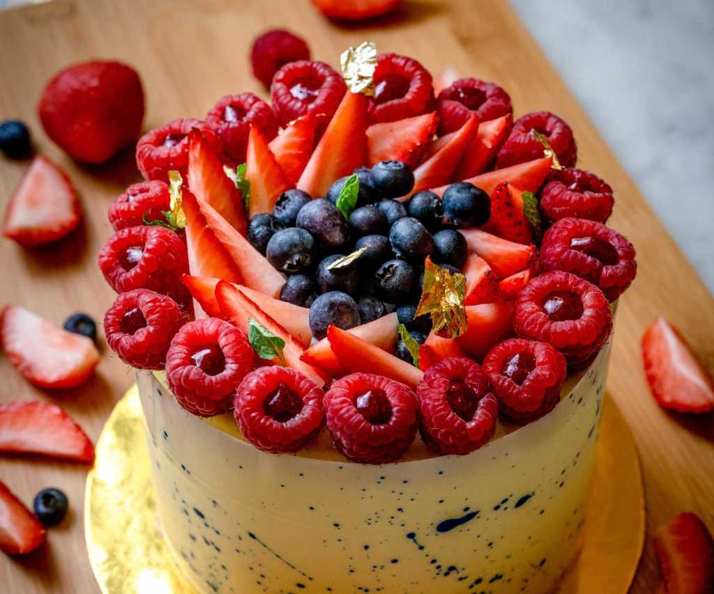 Beautifully decorated cake with fresh fruit like blueberries, strawberries and raspberries