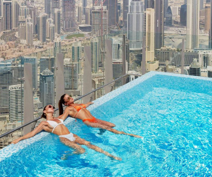 two woman in a sky high infinity pool sunbathing