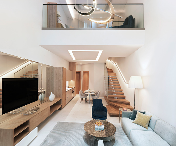 Opulent lofted living room space iwth modern chandeliers and stairs leading up. 