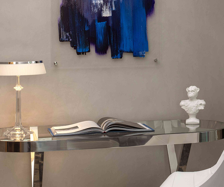A luxurious white chair and desk is accompanied by a mesmerizing blue painting. 