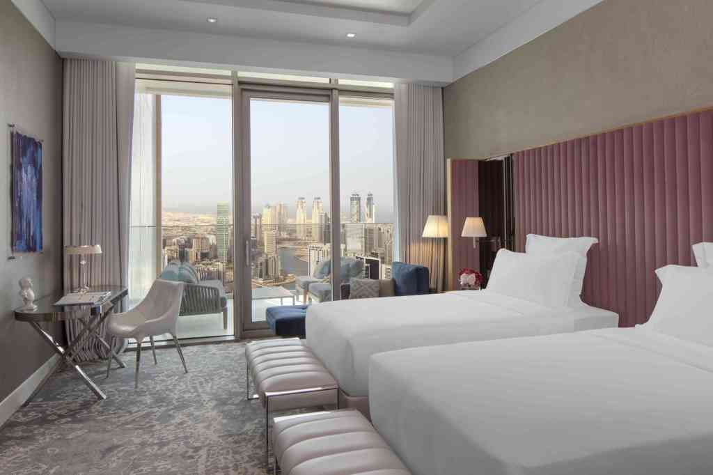 Luxurious hotel room with two beds and stunning city view.