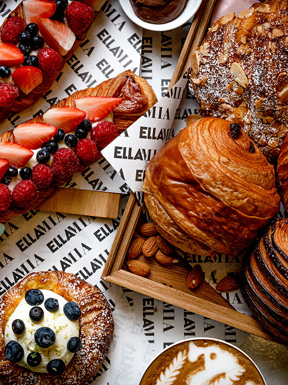 Primer plano de pasteles, incluidos croissants, sobre papel de la marca Ellamia.
