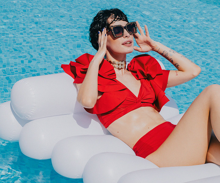 Woman in red bikini and sunglasses relaxing on inflatable pool float.
