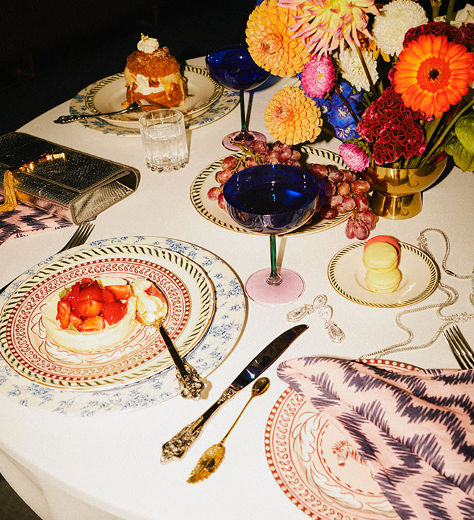 Un lujoso comedor con platos ornamentados, un postre, macarons y cóctel azul.