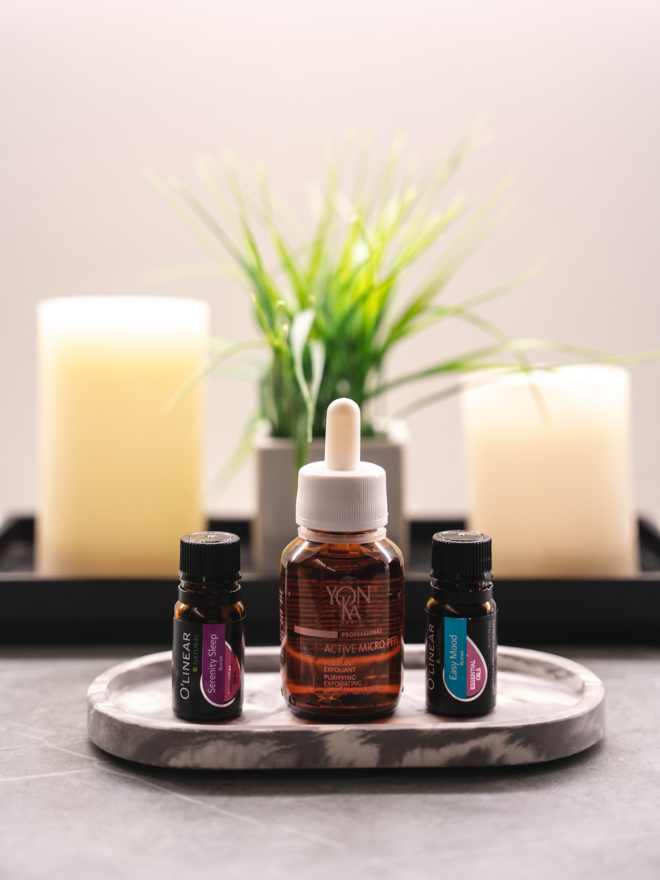 three essential oils sitting on a tray with candles in the background