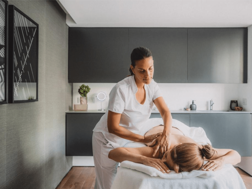 a massage therapist massaging a guest in a relaxing treatment room