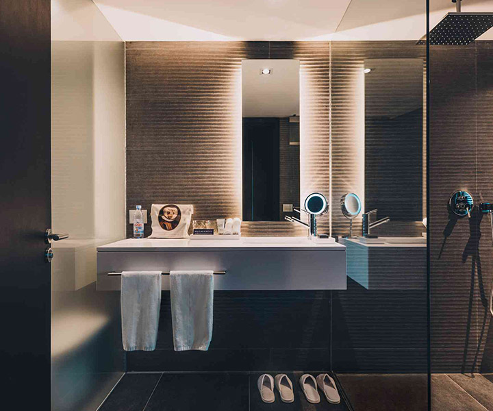 Salle de bain luxueuse avec lavabo élégant, grand miroir et douche moderne.