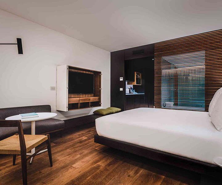 Quarto luxuoso com uma cama macia, uma TV compacta e um elegante pavimento de madeira.
