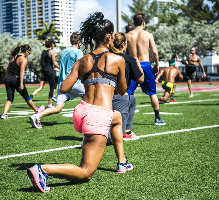 Pessoas a participar num copo de fitness ao ar livre num campo relvado em Miami