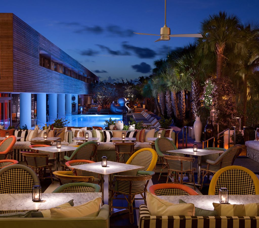 Outdoor patio at night at Bar Central at SLS South Beach with vibrant chairs and tables, creating a lively and inviting ambiance.