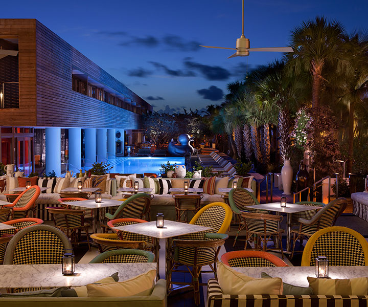 Outdoor patio at night at Bar Central at SLS South Beach with vibrant chairs and tables, creating a lively and inviting ambiance.