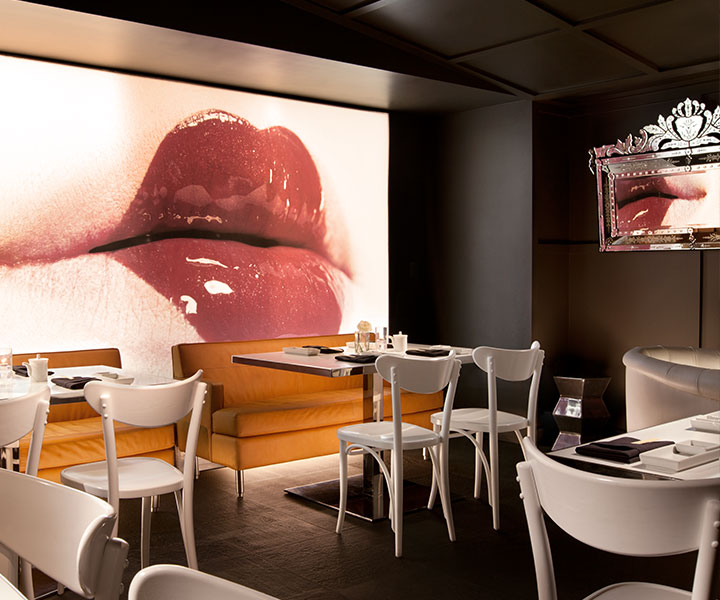 Interior do restaurante Katsuya South Beach, com mesas e cadeiras brancas e um grande mural com os lábios de uma mulher.