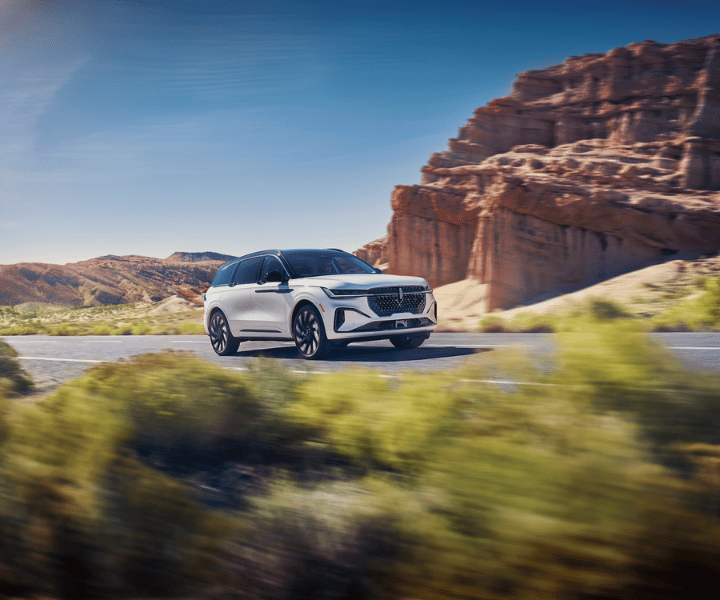 a white lincoln SUV driving through the desert