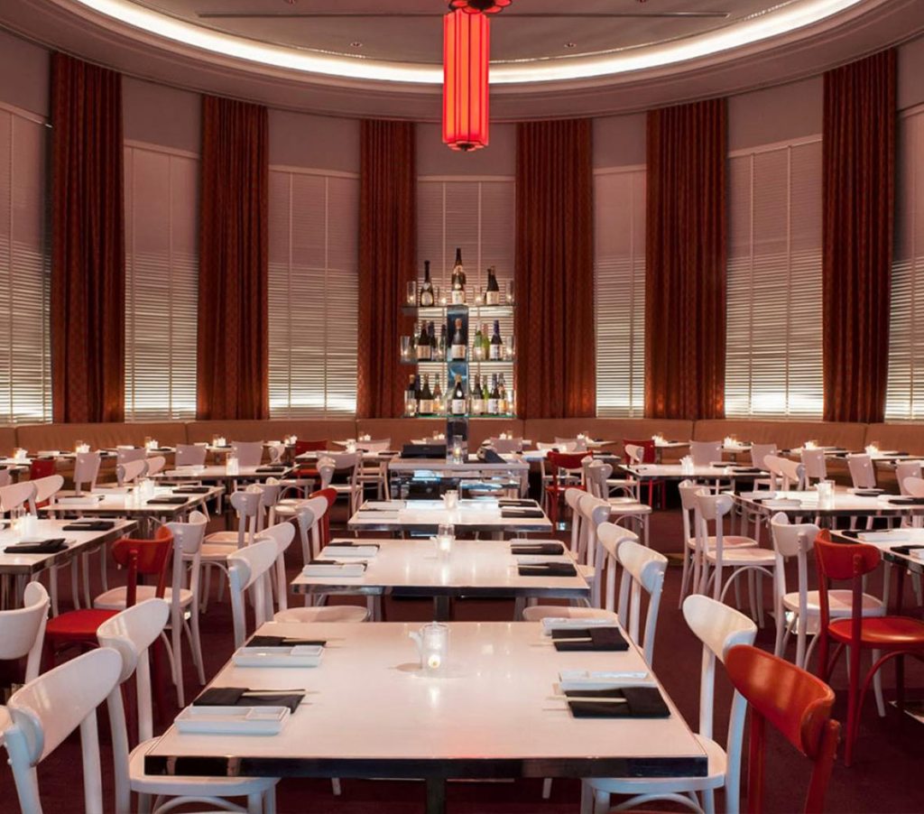 Elegante restaurante Katsuya, adornado com assentos em tons de carmesim e marfim, irradiando opulência e sofisticação.