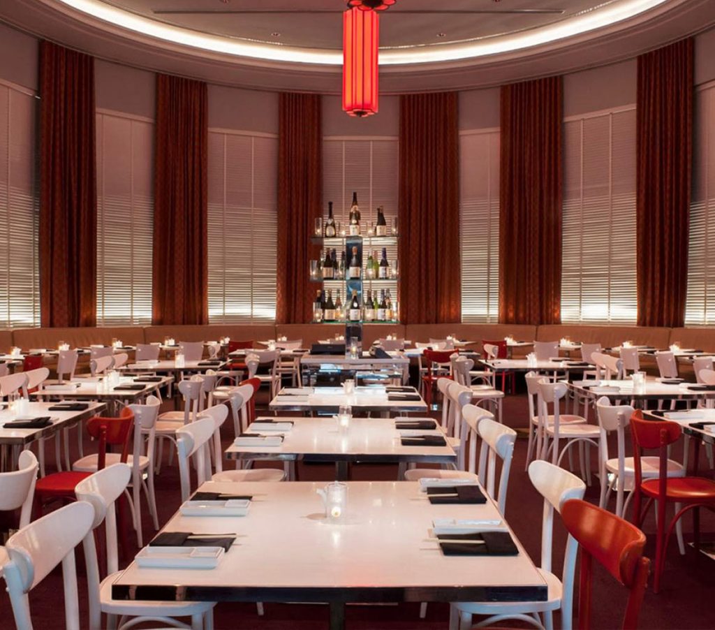 Elegant Katsuya restaurant adorned with crimson and ivory seating arrangements, exuding opulence and sophistication.