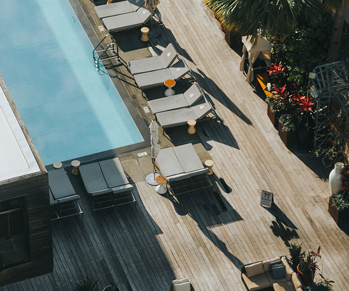 Vista aérea de um deck de piscina com muitas espreguiçadeiras.