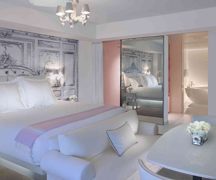 Luxurious hotel room with plush bed, elegant bathtub, and stylish mirror.