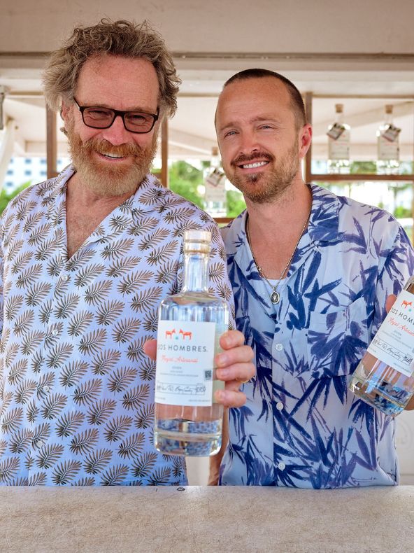 Celebrity founders behind Dos Hombres tequila holding liquor bottles.