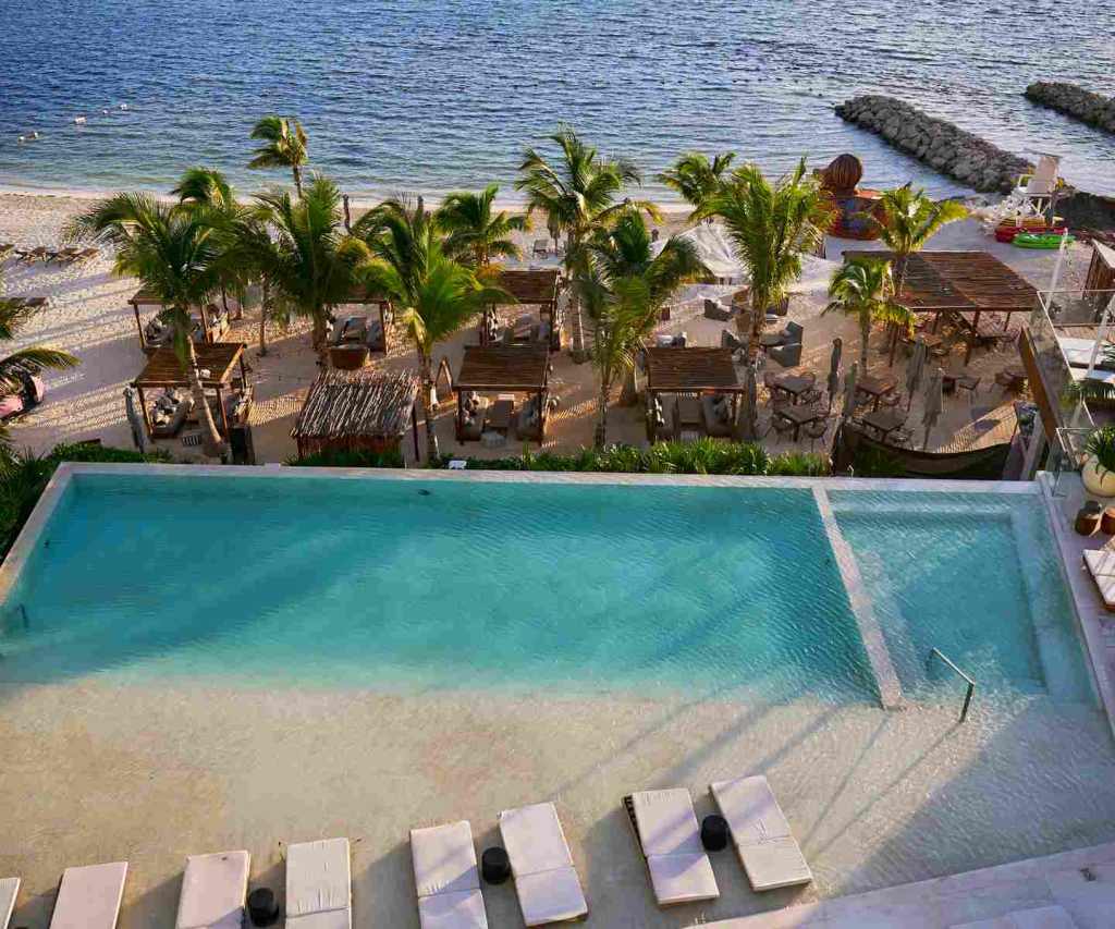 piscina infinita com espreguiçadeiras com vista para a praia e o oceano