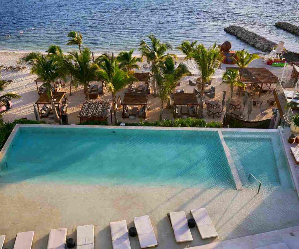 Piscine à débordement avec méridiennes donnant sur la plage et l’océan