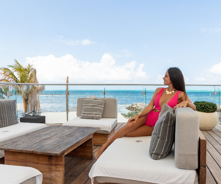 a woman in a pink swimsuit is lounging on a luxurious terrace with ocean views