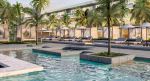 A rendering of a pool lined with palm trees, loungers and cabanas, with a hotel building in the background.