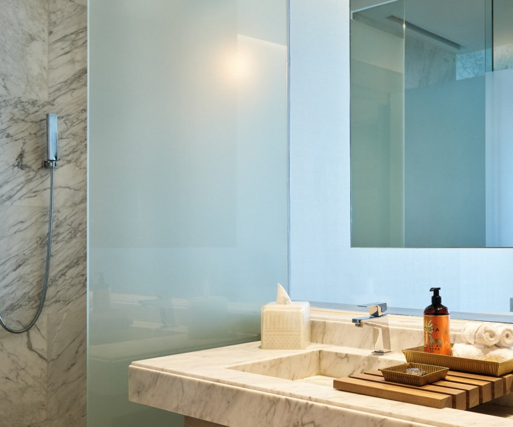 a marble vanity with two bathroom sinks and luxury bath amenities on the counter