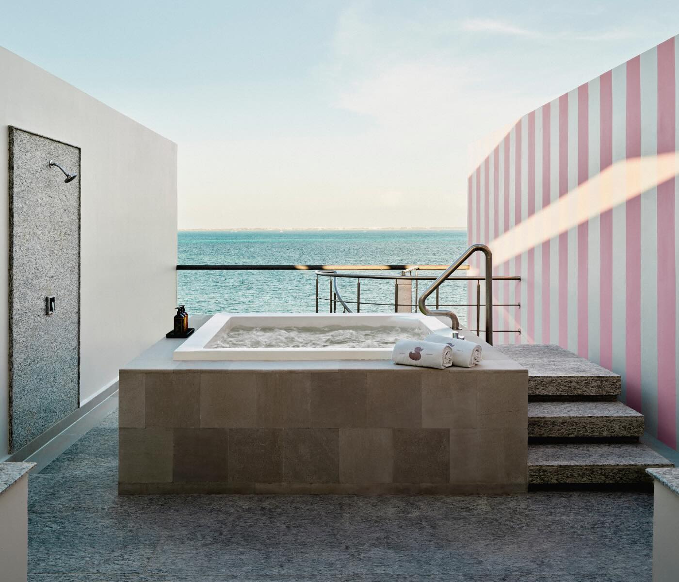 a rooftop hot tub with an outdoor shower overlooking the ocean