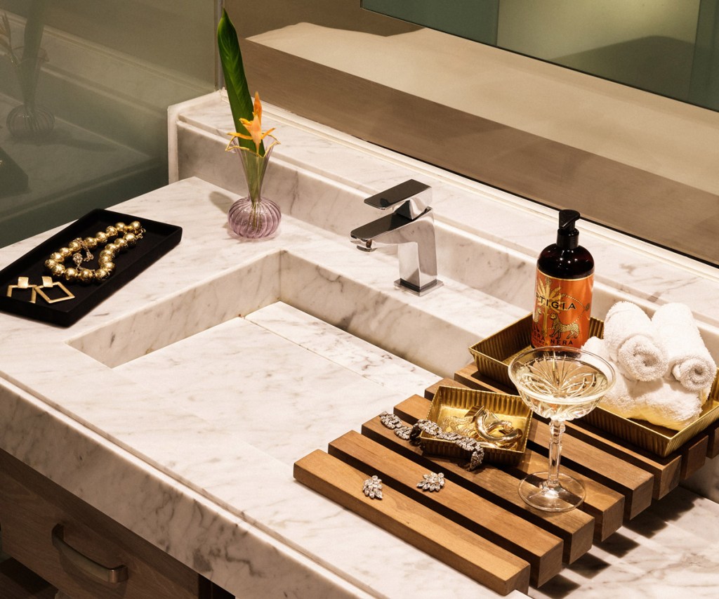 a close up of the vanity in the bathroom with white marble and jewelry on the side as well as bath amenities