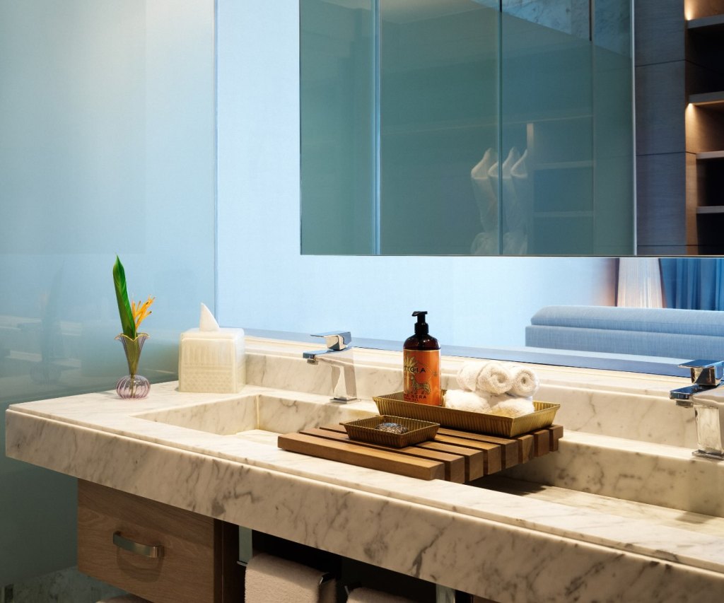 a marble vanity with two bathroom sinks and luxury bath amenities on the counter