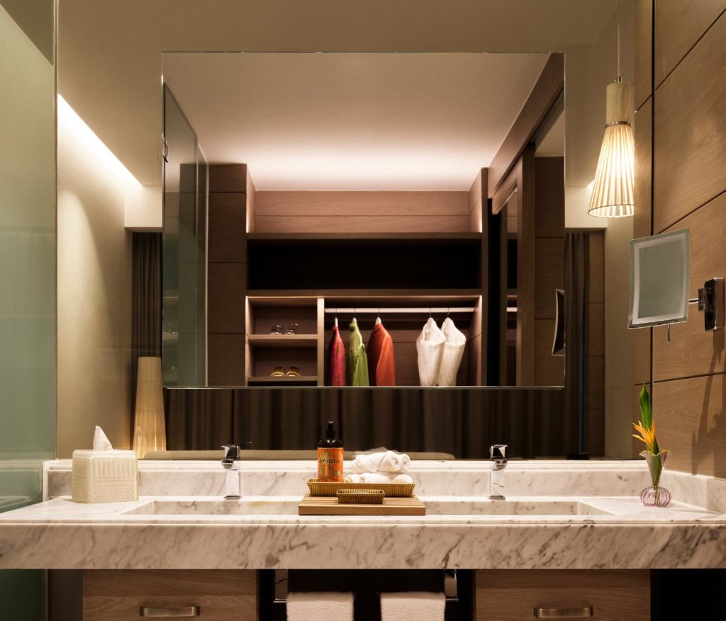 a beautiful bathroom with a marble countertop and two sinks, with a mirror reflecting the closet behind