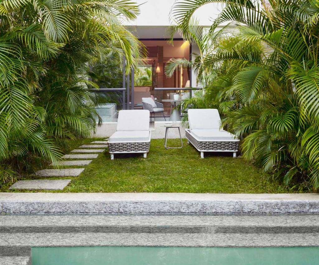 two lounge chairs on the grass in front of a swim out room