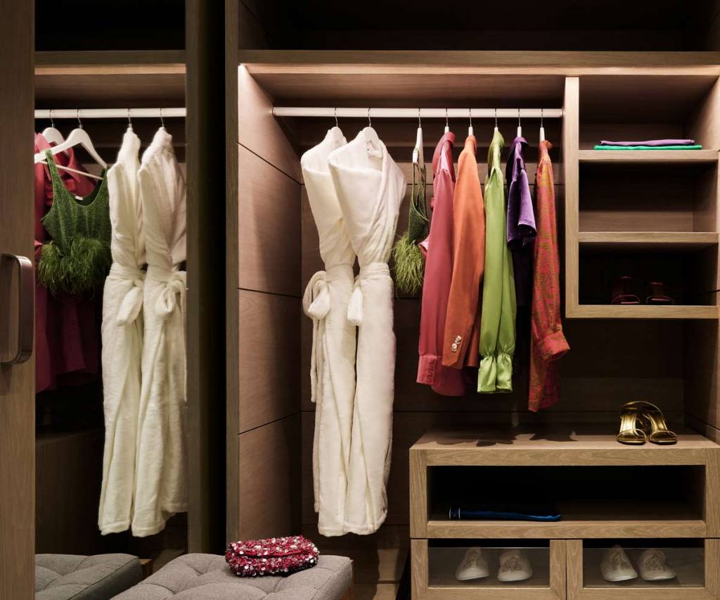 a closet in a room at sls playa mujeres with two luxurious robes hanging as well as other colorful clothing