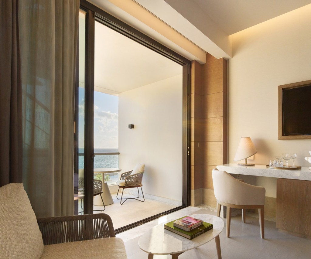 a desk in a room at sls playa mujeres with an hdtv mounted on the wall in front of it with a sliding glass door leading out to a deck